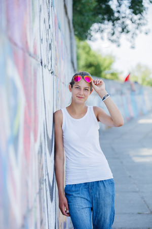 Girl wearing blank white t-shirt, jeans posing against rough street wallの写真素材