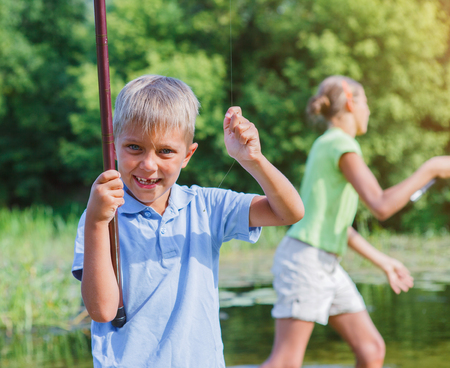 Lonely little child fishing on riverの写真素材