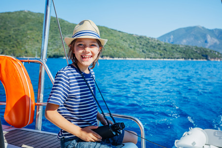 Little boy on board of sailing yacht on summer cruise. Travel adventure, yachting with child on family vacation.の写真素材