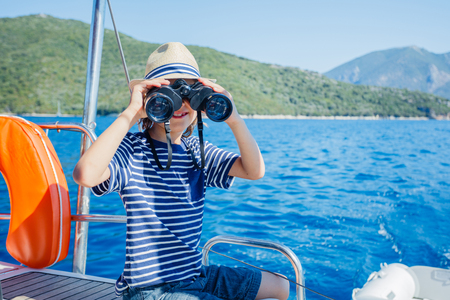 Little boy on board of sailing yacht on summer cruise. Travel adventure, yachting with child on family vacation.の写真素材