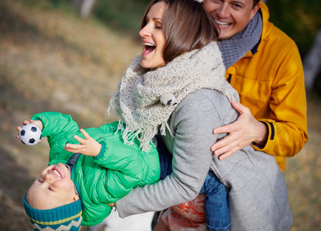 Happy family playing in autumn parkの写真素材