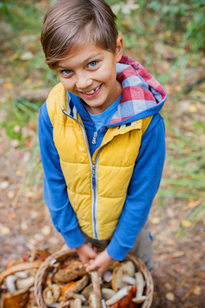 Cute boy with wild mushroom found in the forestの写真素材