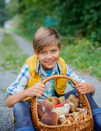 Cute boy with wild mushroom found in the forestの写真素材