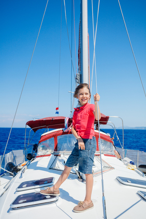 Little boy on board of sailing yacht on summer cruise. Travel adventure, yachting with child on family vacation.の写真素材