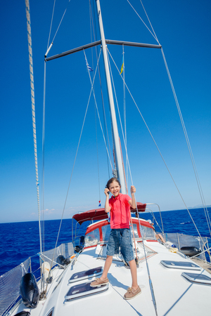 Little boy on board of sailing yacht on summer cruise. Travel adventure, yachting with child on family vacation.の写真素材
