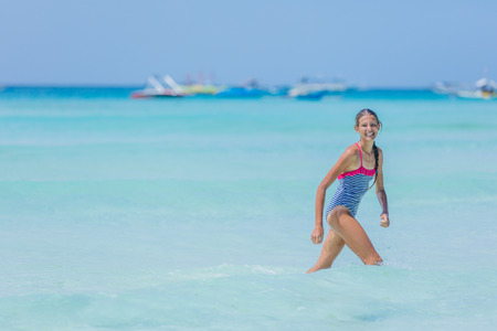 Girl in swimsuit runing and having fun on tropical beachの写真素材