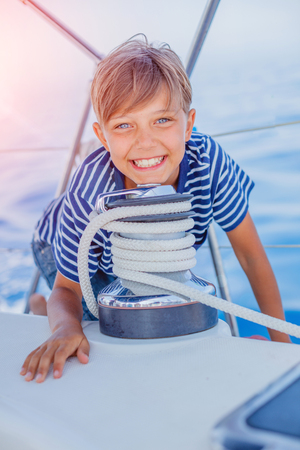 Little boy on board of sailing yacht on summer cruise. Travel adventure, yachting with child on family vacation.の写真素材