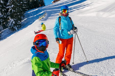Cute skier boy with his mother in a winter ski resort.の写真素材