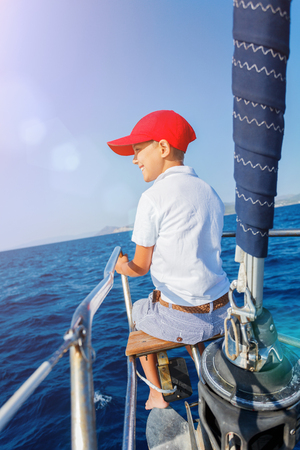 Little boy on board of sailing yacht on summer cruise. Travel adventure, yachting with child on family vacation.の写真素材