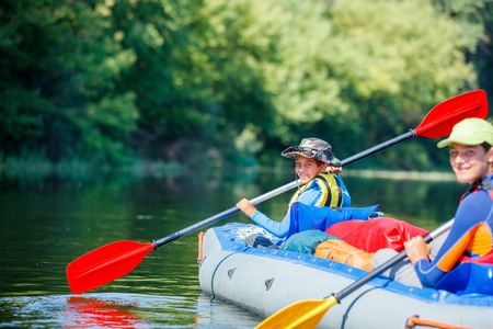 Happy kids kayaking on the river on a sunny day during summer vacationの写真素材