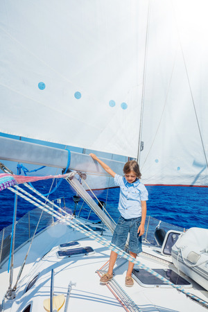 Little boy on board of sailing yacht on summer cruise. Travel adventure, yachting with child on family vacation.の写真素材