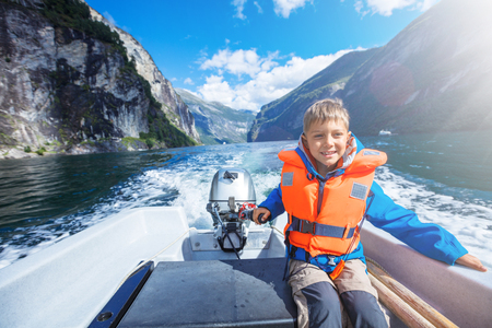 Portrait of young boy driving the motorboat on the Geirangerfjord, Norway.の写真素材