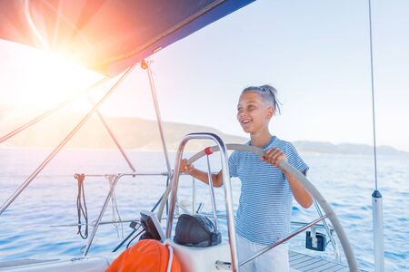 Little boy on board of sailing yacht on summer cruise. Travel adventure, yachting with child on family vacation.の写真素材