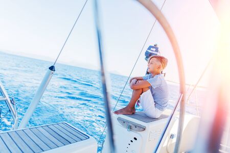 Little boy on board of sailing yacht on summer cruise. Travel adventure, yachting with child on...