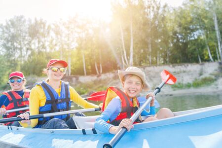 Happy boy kayaking on the river on a sunny day during summer vacationの写真素材