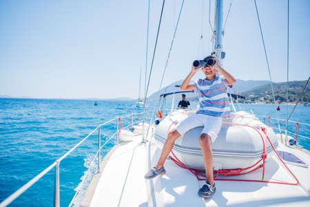 Little boy on board of sailing yacht on summer cruise. Travel adventure, yachting with child on family vacation.の写真素材