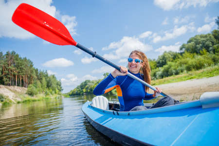 Happy family kayaking on the river on a sunny day during summer vacationの写真素材