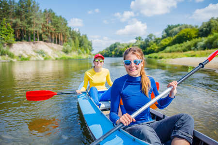 Happy girls kayaking on the river on a sunny day during summer vacationの写真素材