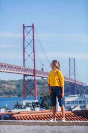 Portugal tourist attractions concept. Attractive brunette girl und 25th April Bridge in Lisbonの写真素材