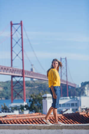 Portugal tourist attractions concept. Attractive brunette girl und 25th April Bridge in Lisbonの写真素材