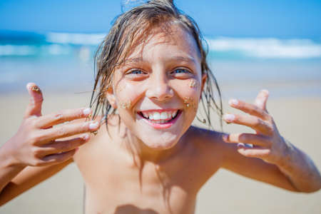 Young boy posing at the summer beach. Cute spectacled smiling happy 12 years old boy at seaside, looking at camera.の写真素材