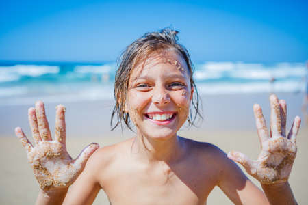 Young boy posing at the summer beach. Cute spectacled smiling happy 12 years old boy at seaside, looking at camera.の写真素材