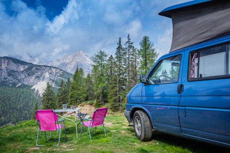 Camper van in the amazing landscape views of forest, mountains. Van road trip holiday and outdoor summer adventureの写真素材