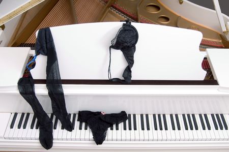 Set of ladies lace lingerie on the keyboard of a white  grand piano.の写真素材