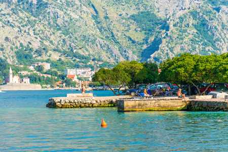 MONTENEGRO, PRCANJ - JUNE 04/2017: tourists come to the shore of the Bay of Kotor in the evening to rest and fish.のeditorial素材