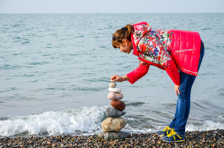 Girl builds a pyramid of colored stones on the Black Sea in Batumi, Georgia.の写真素材