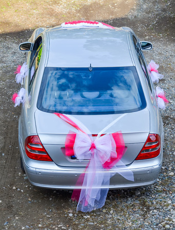 Beautiful wedding car with red and white ribbons.の写真素材