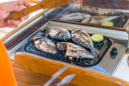 Sea fish is grilled on a grill while sailing on a yacht.の写真素材