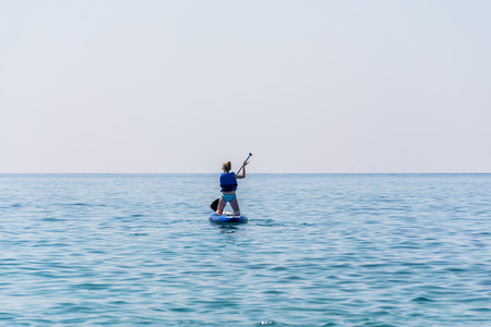 MONTENEGRO, BUDVA - JUNE 05/2017: tourists are engaged in rowing on the board (SUP) on the surface of the calm sea.のeditorial素材