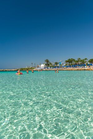 CYPRUS, NISSI BEACH - MAY 12/2018: Tourists relax and swim on one of the most popular beaches on the island.のeditorial素材