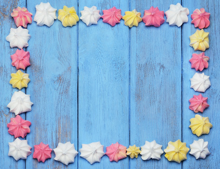 Colorful frame arranged with french vanilla meringue cookies on a blue background.の写真素材