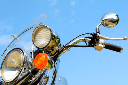 Motorcycle detail closeup front fork and headlight and handlebar. Against the blue sky.の写真素材
