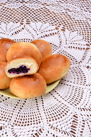 Several yeast rolls with blueberry jam on the table with a white tablecloth.の写真素材