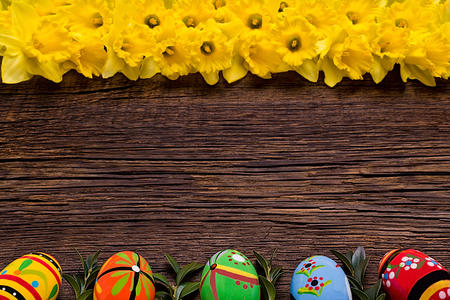 Wooden background with Easter eggs and daffodils.の写真素材