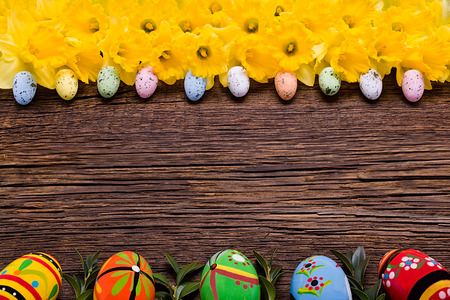 Wooden background with Easter eggs and daffodils.の写真素材