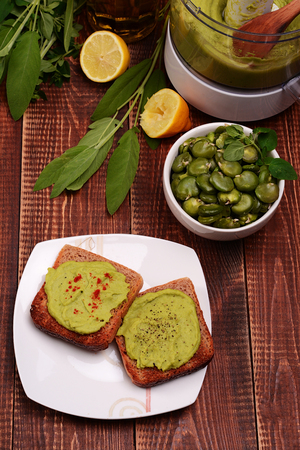 Toast with bean paste and boiled broad beans on wooden background.の写真素材