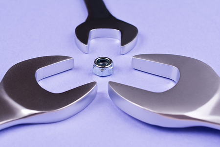 Spanners of various sizes arranged around a screw on a blue background.の写真素材