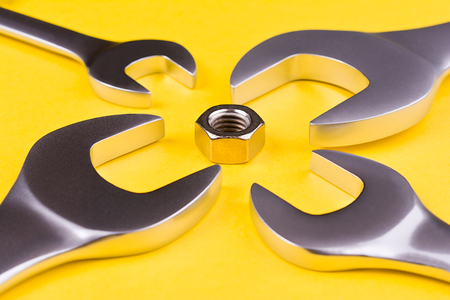 Spanners of various sizes arranged around a screw on a yellow background.の写真素材