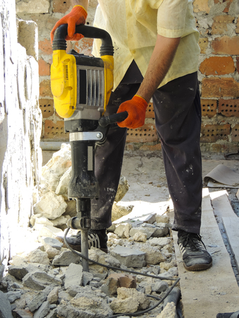 Worker with demolition hammer breaking interior wallの写真素材