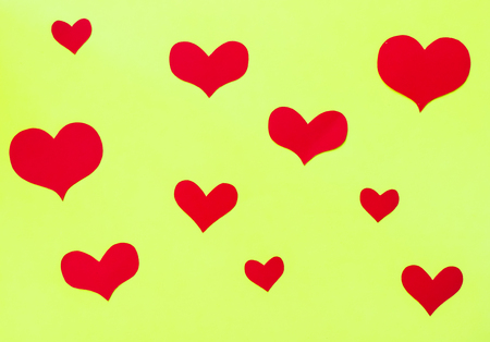 Red paper hearts on a yellow-green paper backgroundの写真素材