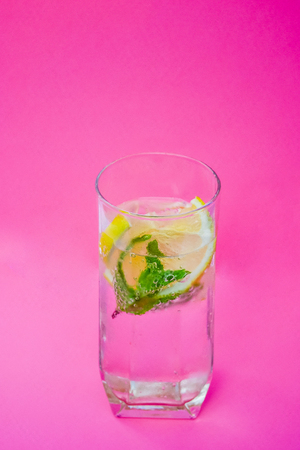 Glass of water, lemon and mint on pink background.の写真素材