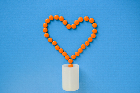 Orange heart from tablets and pills on a blue backgroundの写真素材