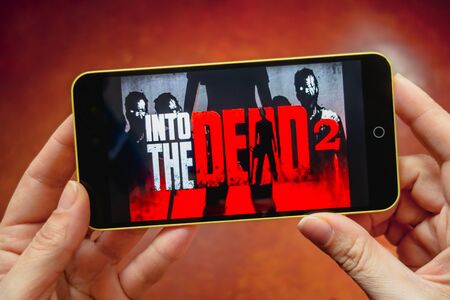 Berdyansk, Ukraine - March 17, 2019: Hands holding a smartphone with Into the dead 2 Mobile game on...