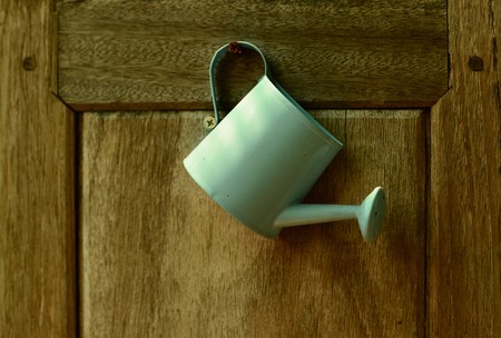 pouring pot water hanging on wood backgroundの写真素材