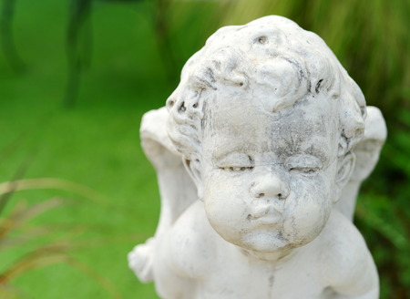 head shot stone sculpture cupid baby on green backgroundの写真素材