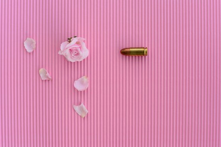 pink rose and metal  bullet on pinl paper backgroundの写真素材